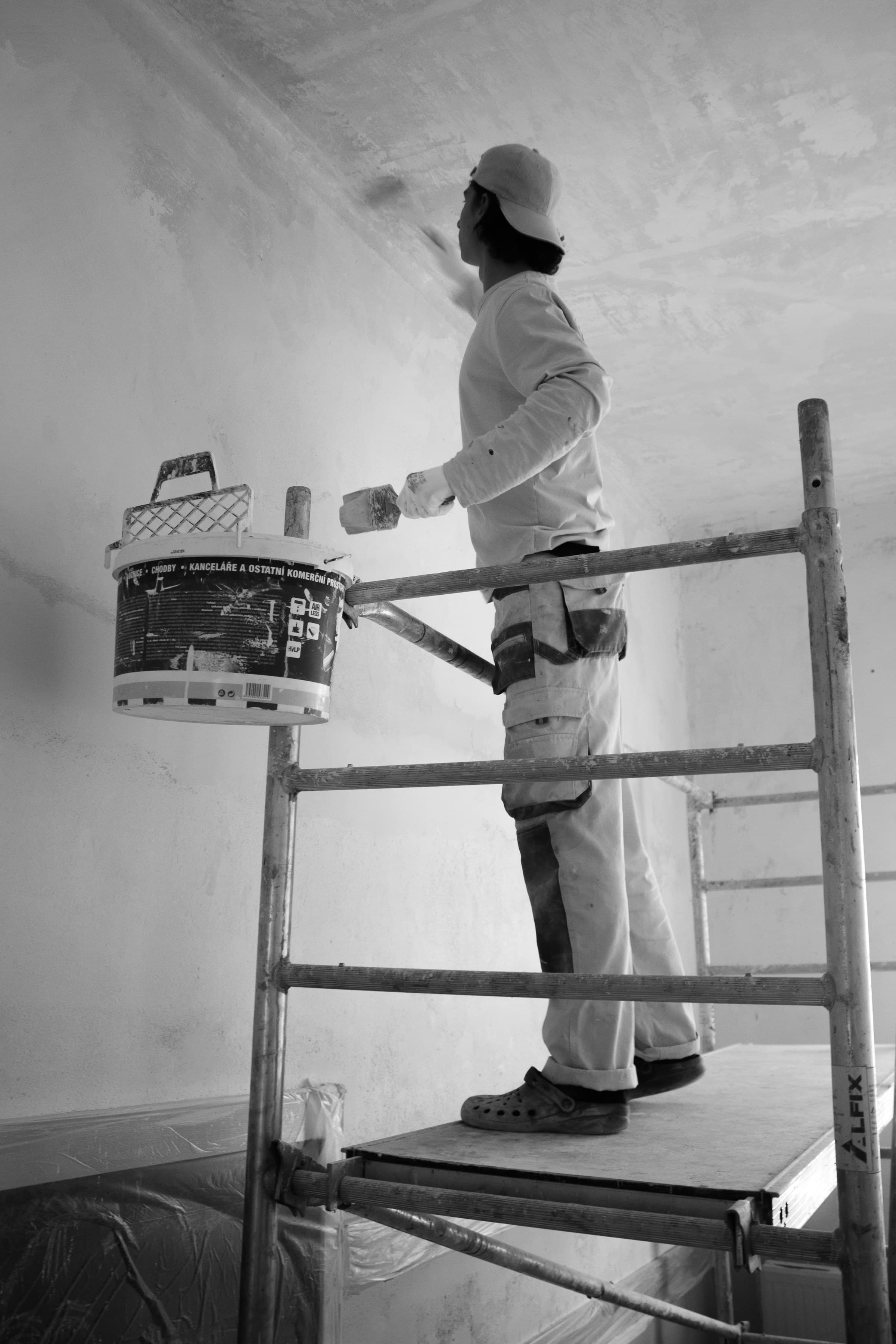 Painter rolling terracotta paint onto a wall mid-job